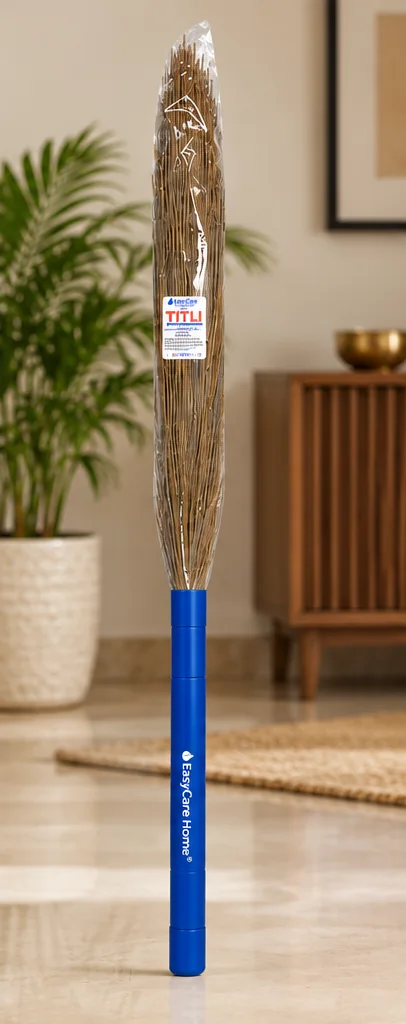 A TITLI grass broom standing on a marble floor in a bright living room beside a potted plant